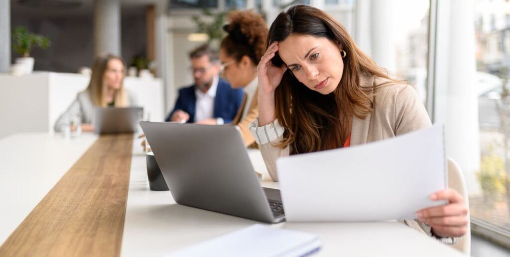 Association professional reviewing documents at a laptop, representing the challenges associations face managing continuing education and member learning without a modern learning management system.