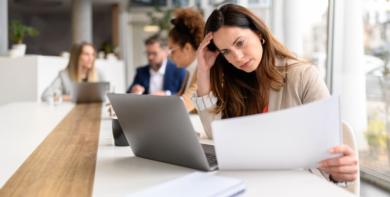 Association professional reviewing documents at a laptop, representing the challenges associations face managing continuing education and member learning without a modern learning management system.